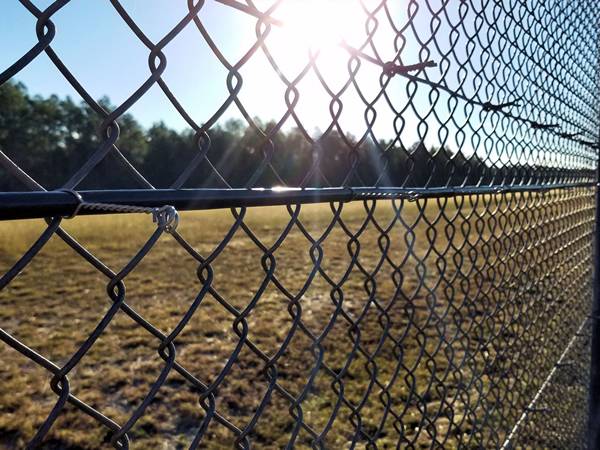 Black chain link fence at sunset.